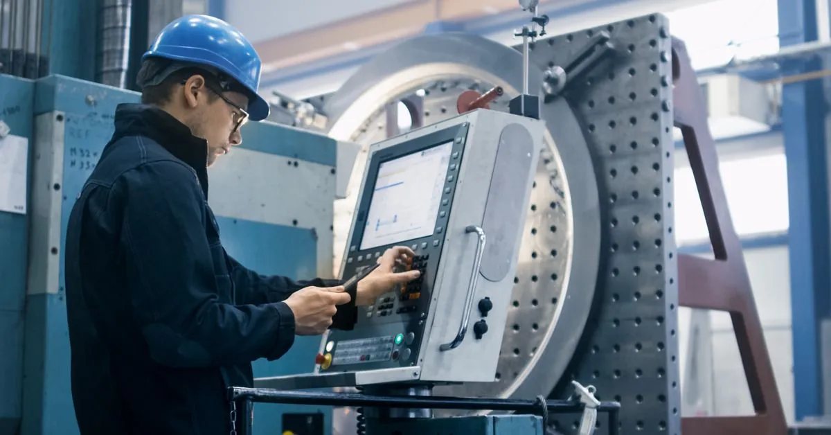 Machinist programming at a CNC control panel on the production floor